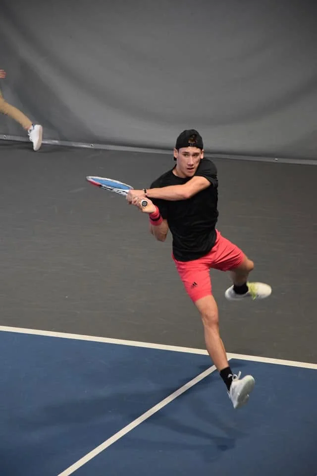 Joueur de tennis frappant un revers sur un court couvert