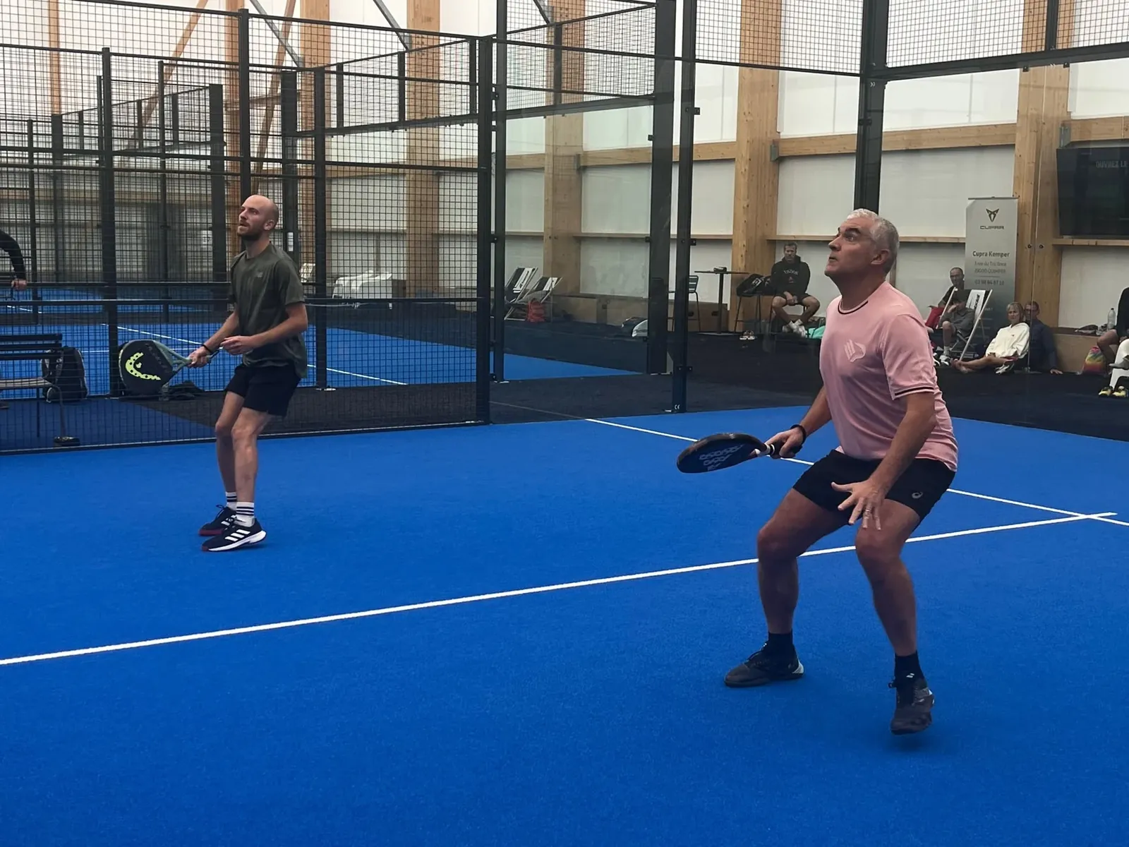 Joueurs de padel en action sur un court couvert du club