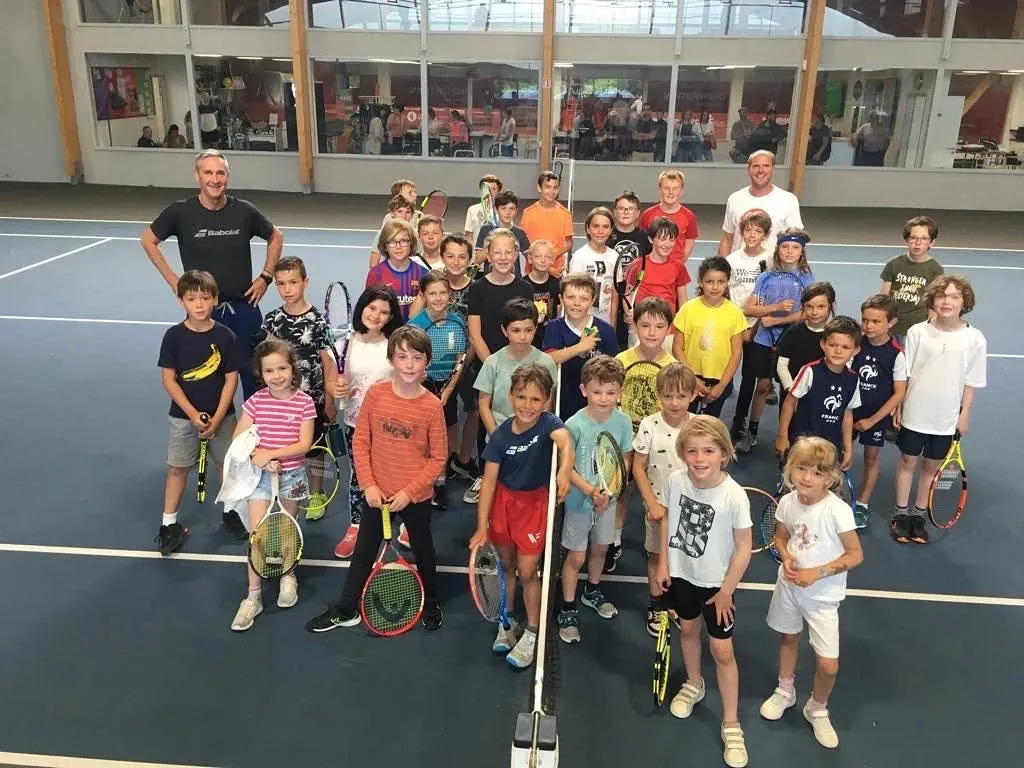 Enfants et entraîneurs réunis sur un court couvert du club